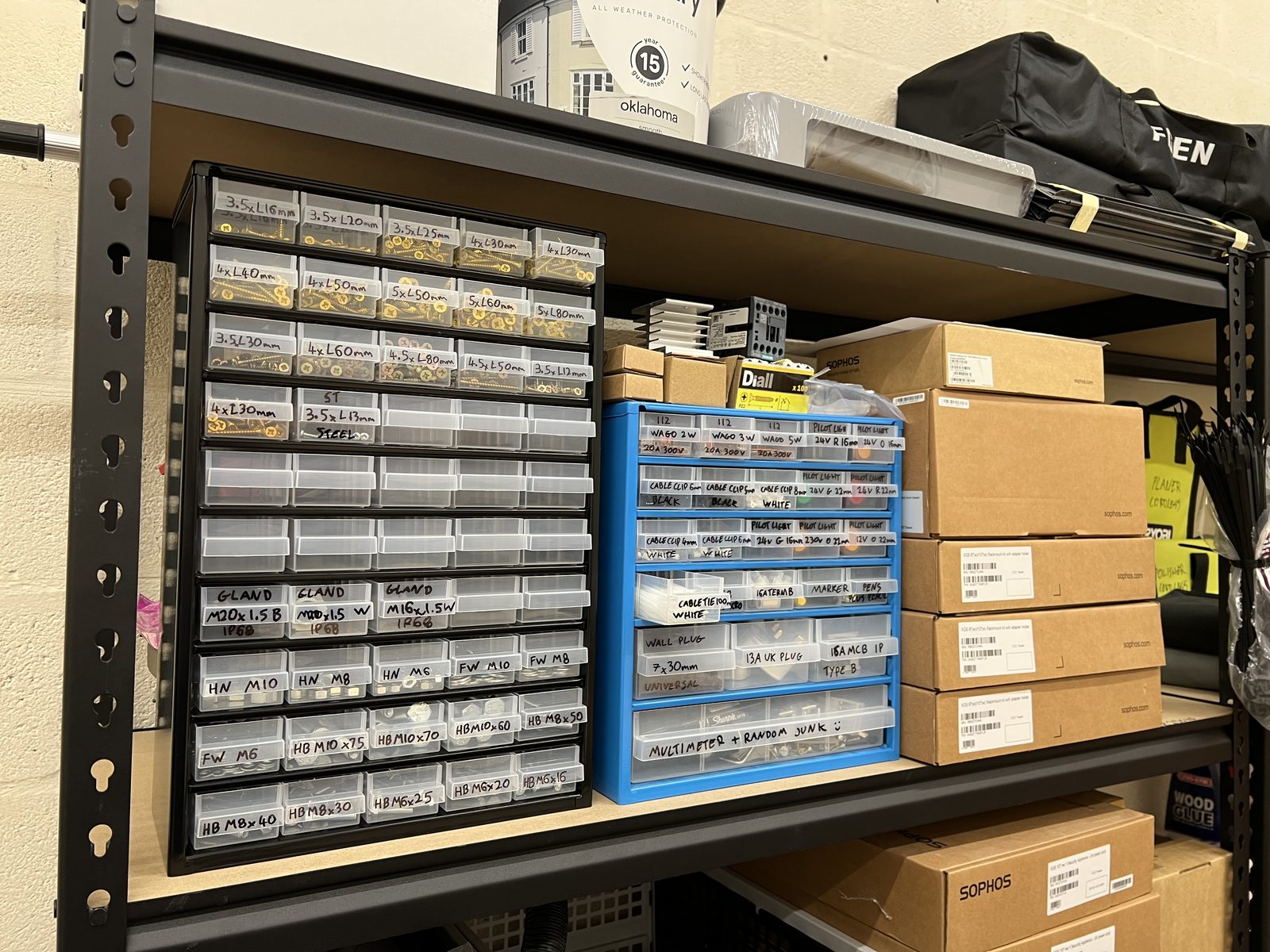 Shelving with two cabinets of small labelled drawers: screws by size, Wago connectors, pilot lights, cable clips and a drawer marked multimeter plus random junk.